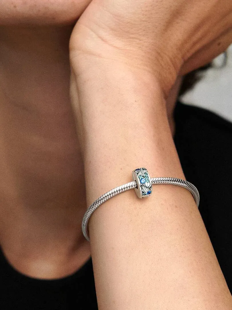 Close-up of the shell and starfish charm on a wrist, side view against a dark background.
