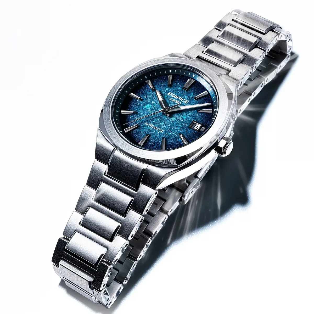 Vista en ángulo del reloj con esfera azul y brazalete de acero sobre fondo blanco.