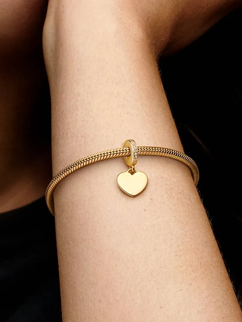 Nahaufnahme des goldenen Herz-Charms an einem Armband, getragen am Handgelenk eines Models.