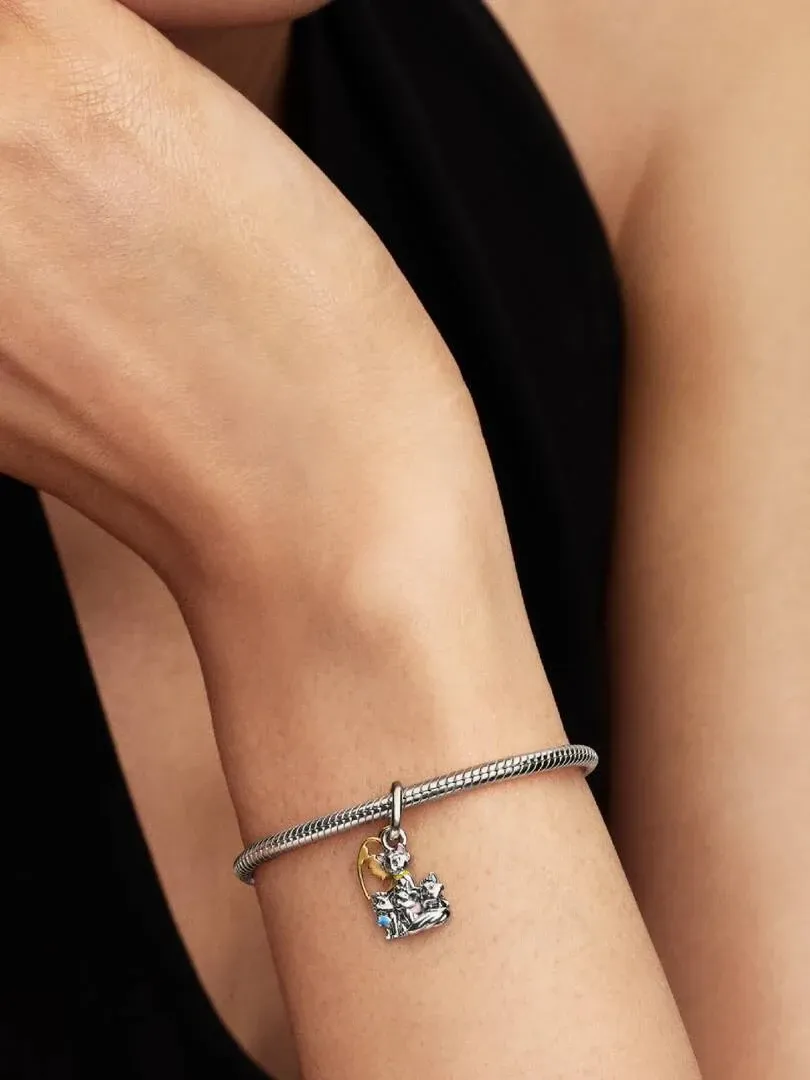 Close-up of a wrist wearing the hanging charm on a silver bracelet, against a black background.