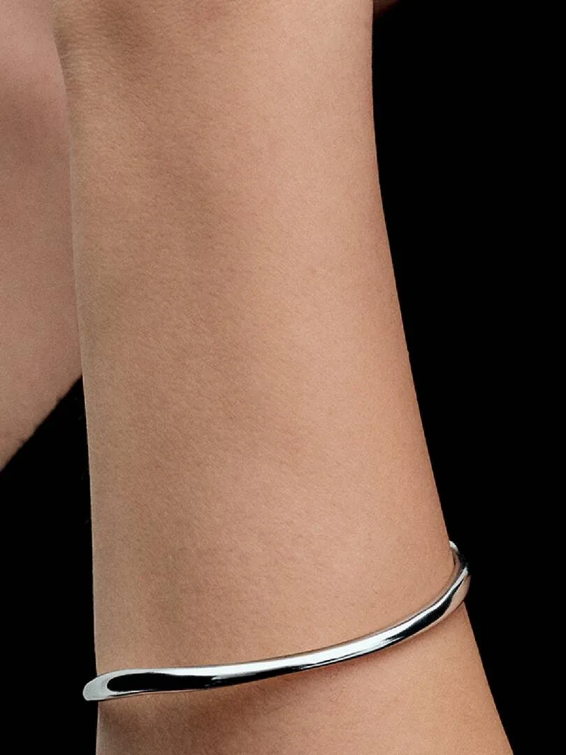 Close-up of the bangle on a wrist, side view against a black background.