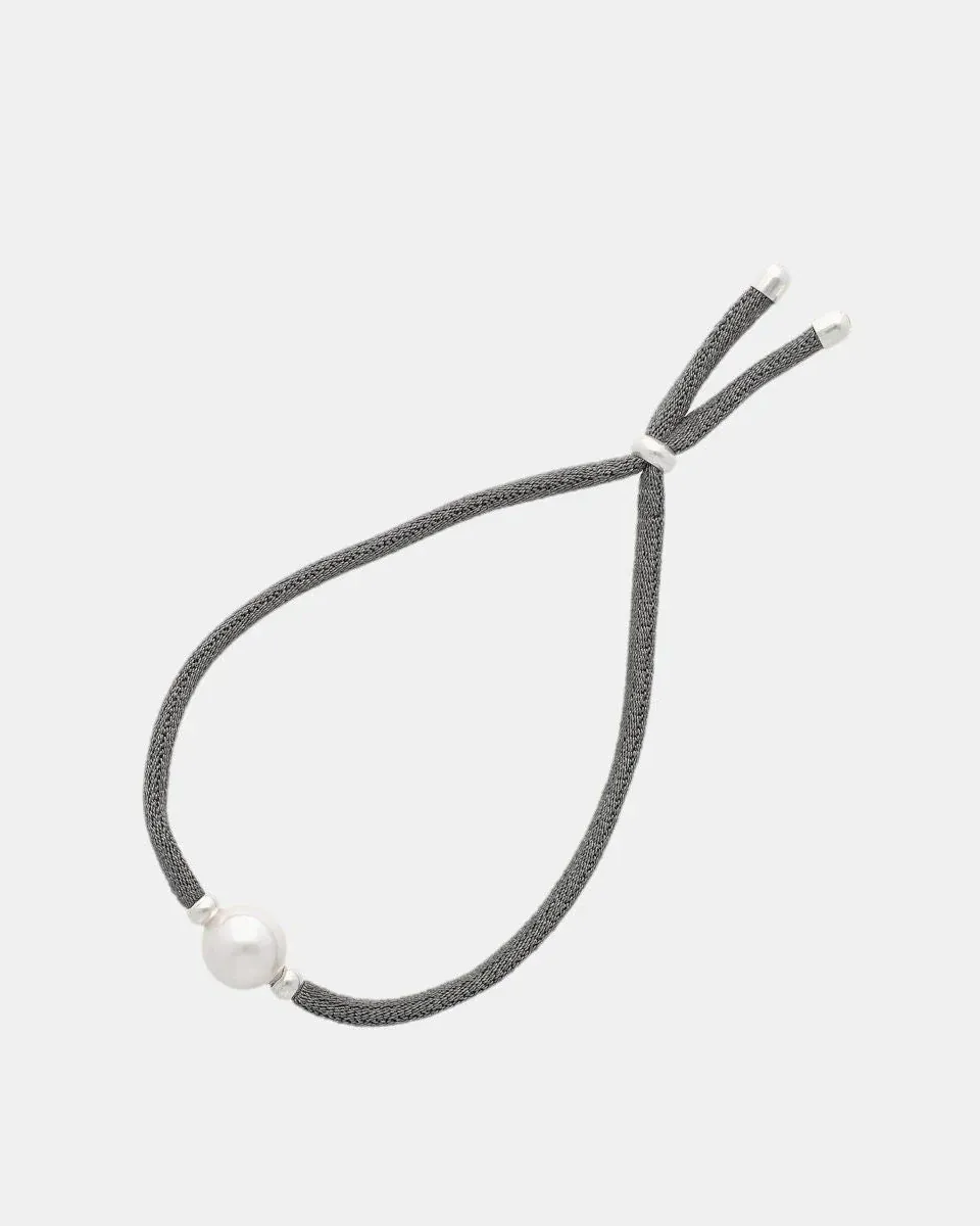 Pulsera elástica gris con perla blanca central, vista frontal sobre fondo blanco puro.