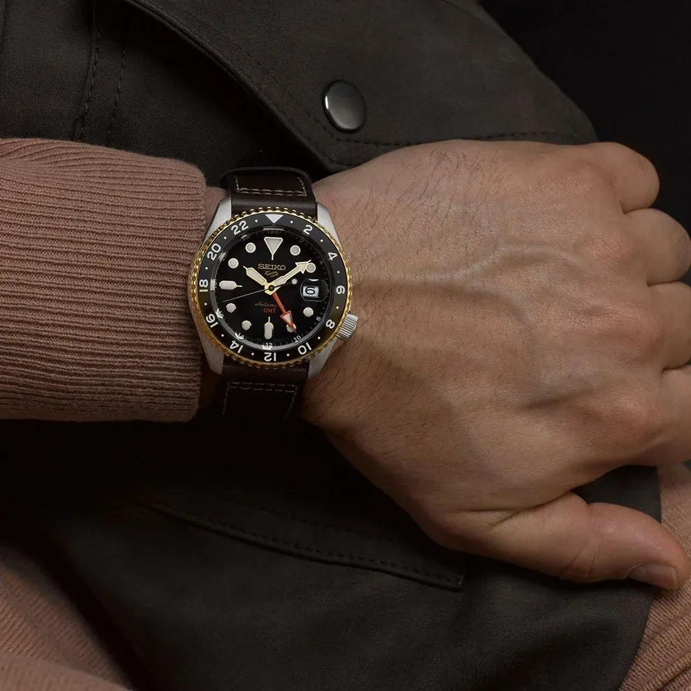 Reloj puesto en muñeca masculina, plano detalle, fondo de chaqueta marrón y jersey beige