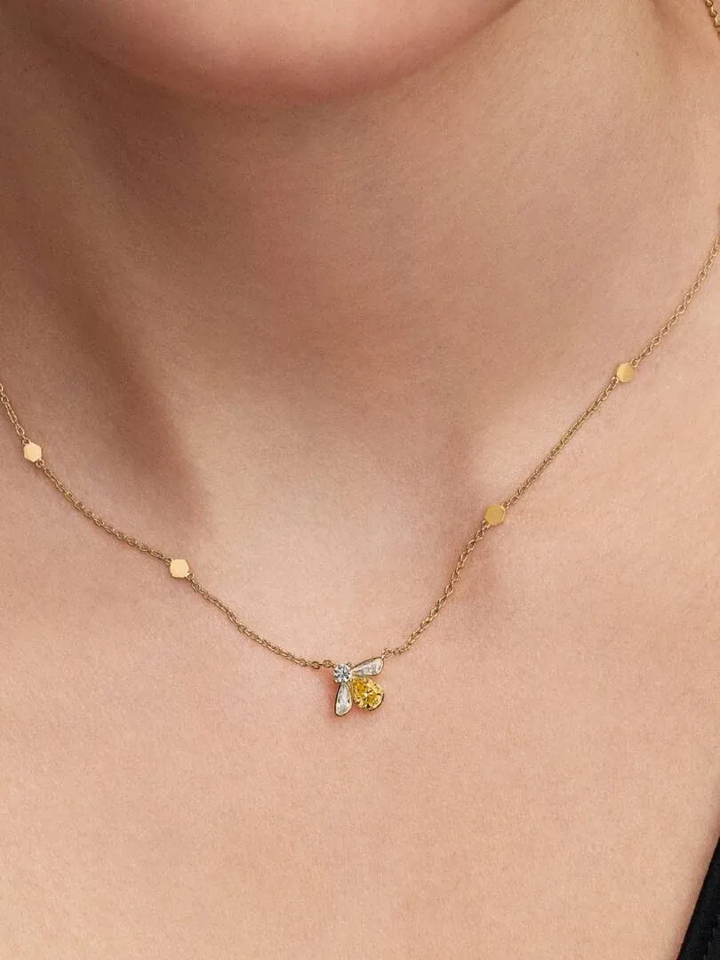 Close-up of the bee pendant necklace worn on a model's neck, front view.