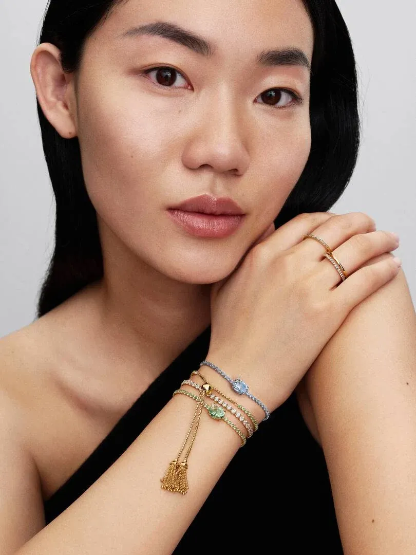 Close-up of wrist wearing stacked bracelets, side view against a neutral background.