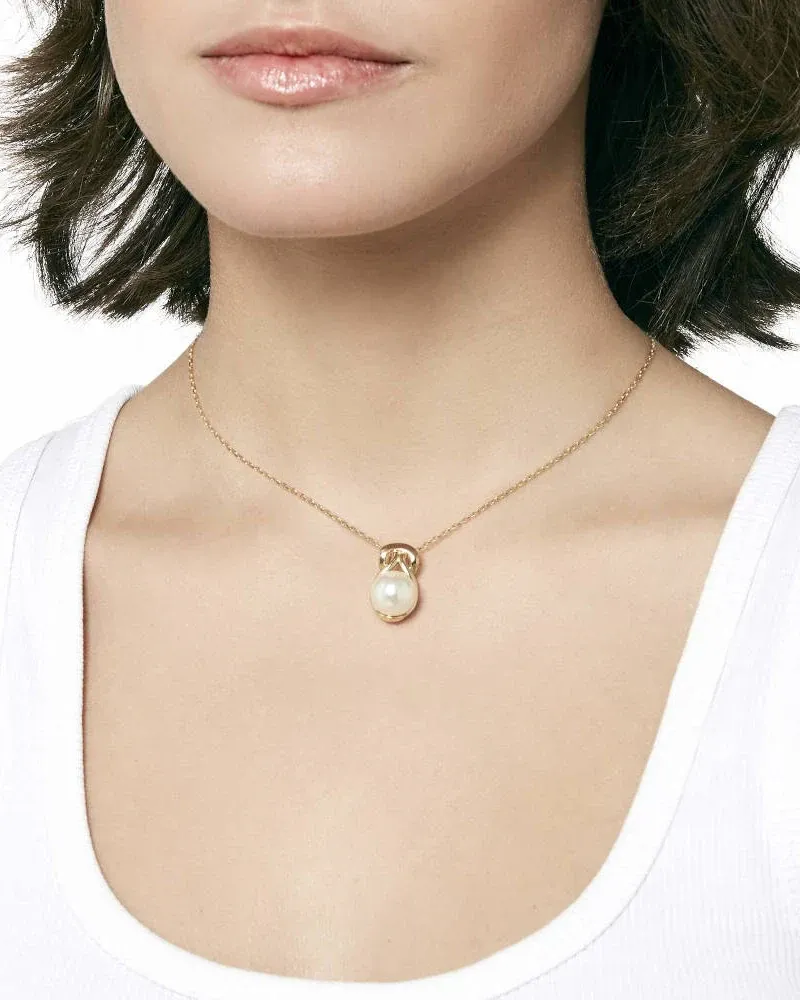 Primer plano del collar con perla blanca sobre el cuello de una modelo, toma frontal con fondo neutro.