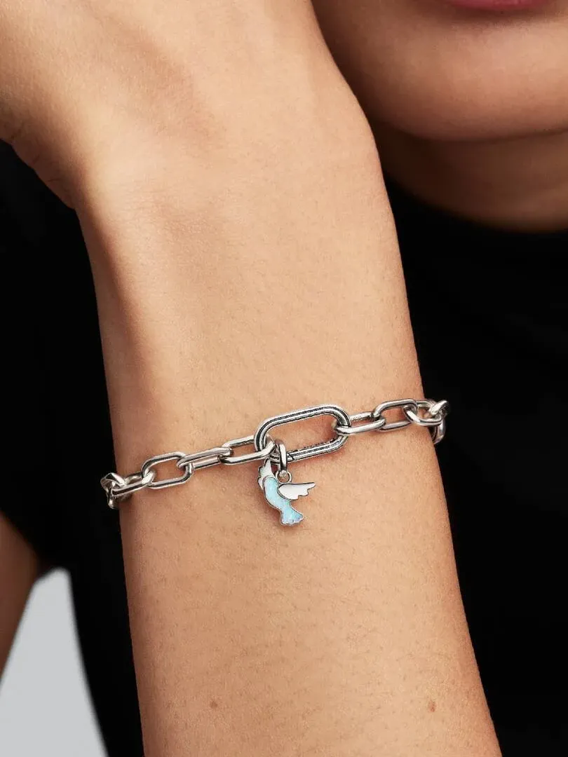 Close-up van een pols met een schakelarmband en een witte duif charm, wazige achtergrond.