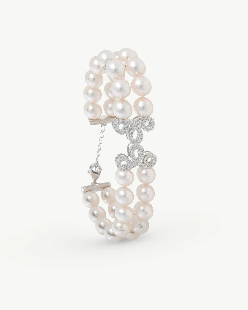 Pulsera de perlas doble vista en ángulo lateral, fondo blanco, detalle del cierre y diseño de circonitas.