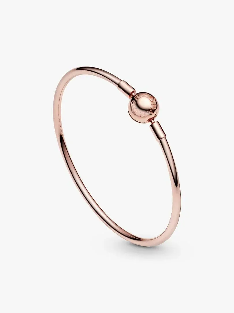 Bracelet jonc vu sous un angle diagonal sur fond blanc, gros plan sur le fermoir sphérique logotypé.