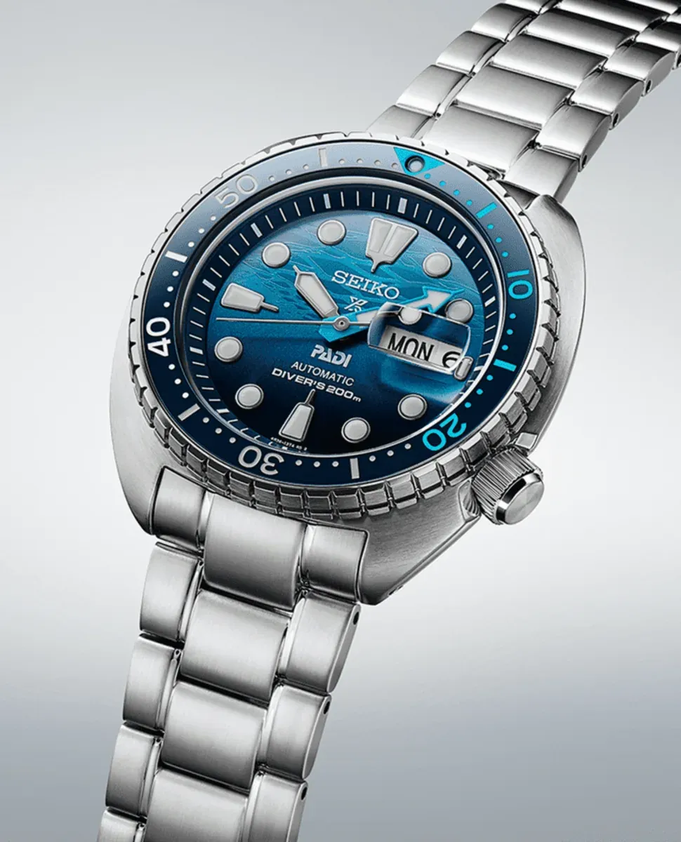 Vue en perspective de la montre complète avec bracelet en acier, fond neutre dégradé.