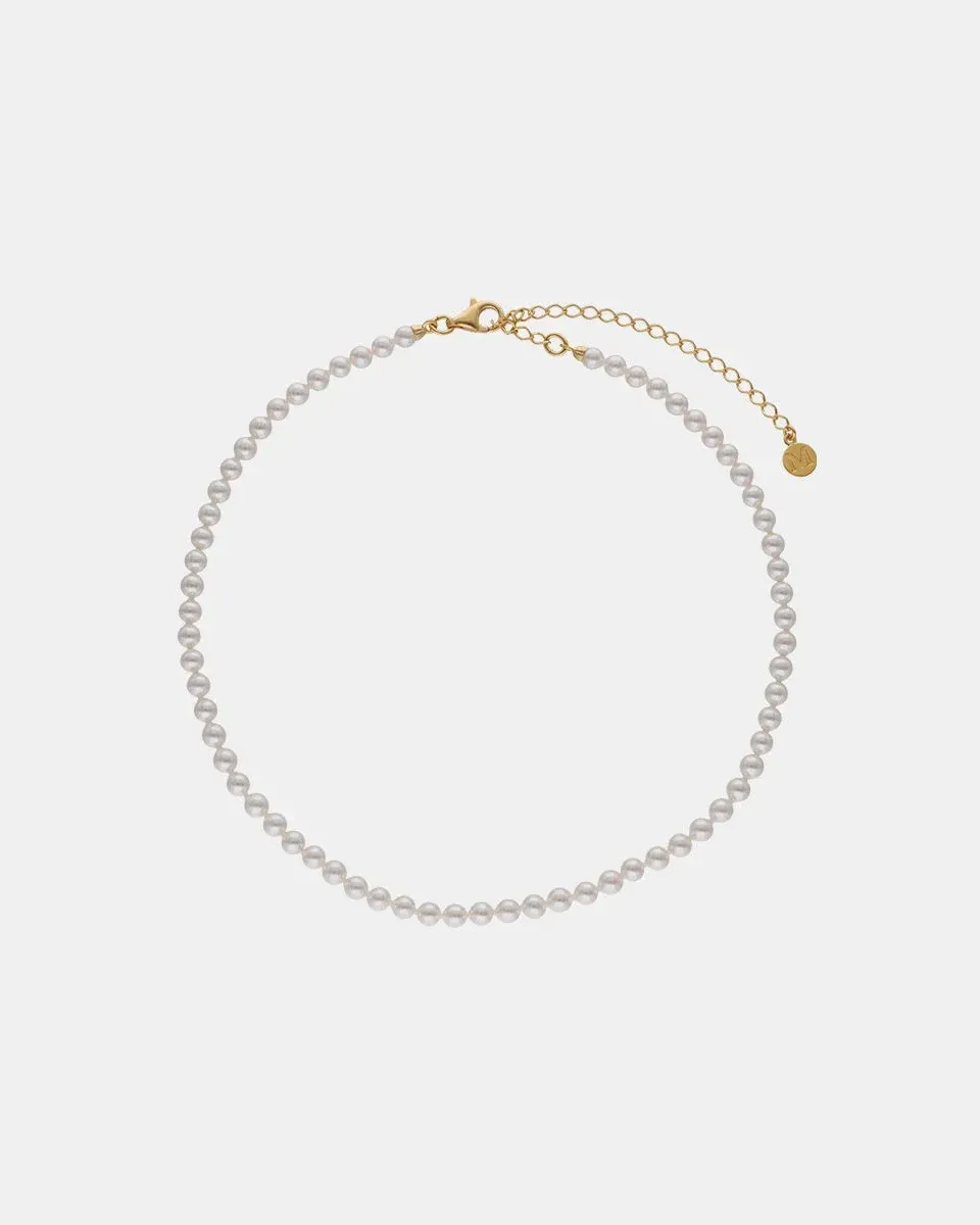Collar de perlas dispuesto en círculo sobre fondo blanco, vista frontal con cierre y cadena de extensión visibles.