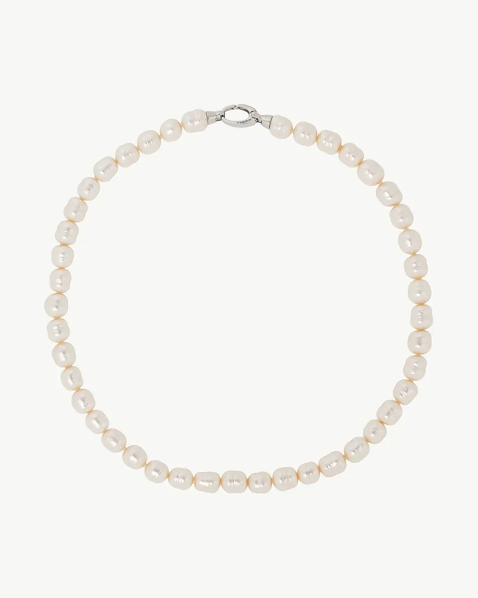 Collar de perlas barrocas blancas dispuesto en círculo sobre fondo blanco, vista cenital con cierre visible.