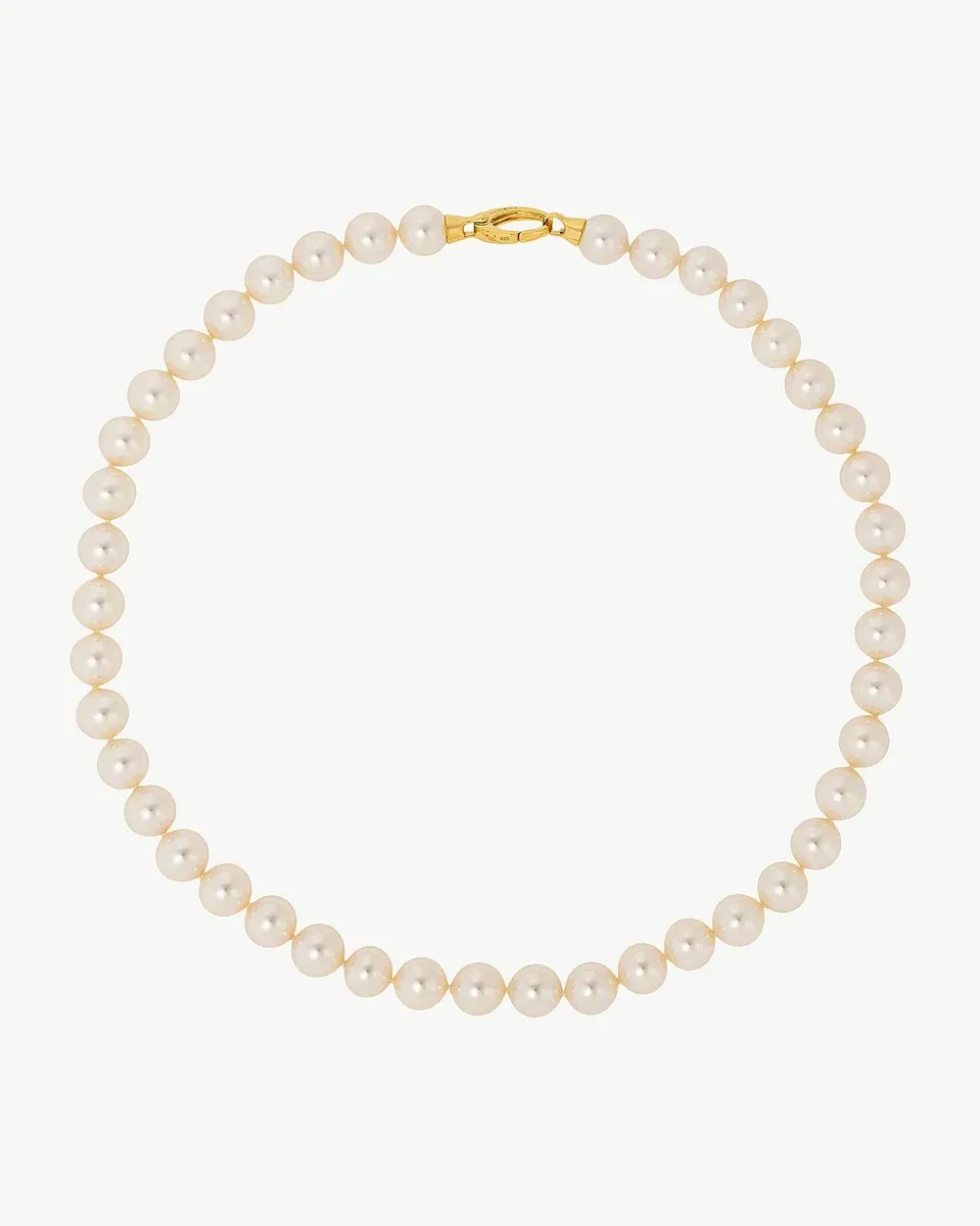 Collar de perlas dispuesto en círculo sobre fondo blanco, vista frontal con cierre dorado visible.