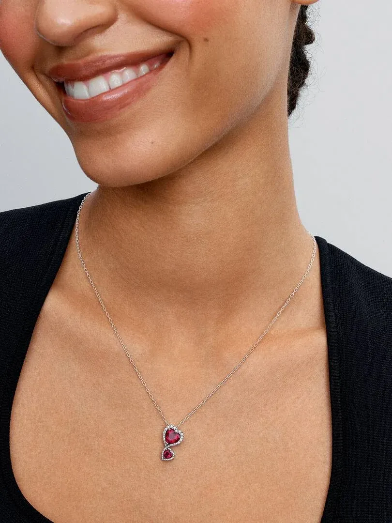 Close-up of the red heart pendant necklace worn on a model's neck against a dark background.