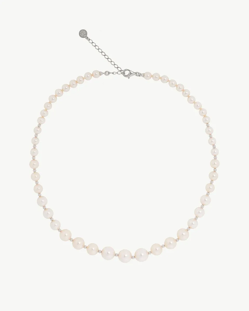 Collar de perlas dispuesto en forma circular sobre fondo blanco, vista frontal completa con cierre visible.