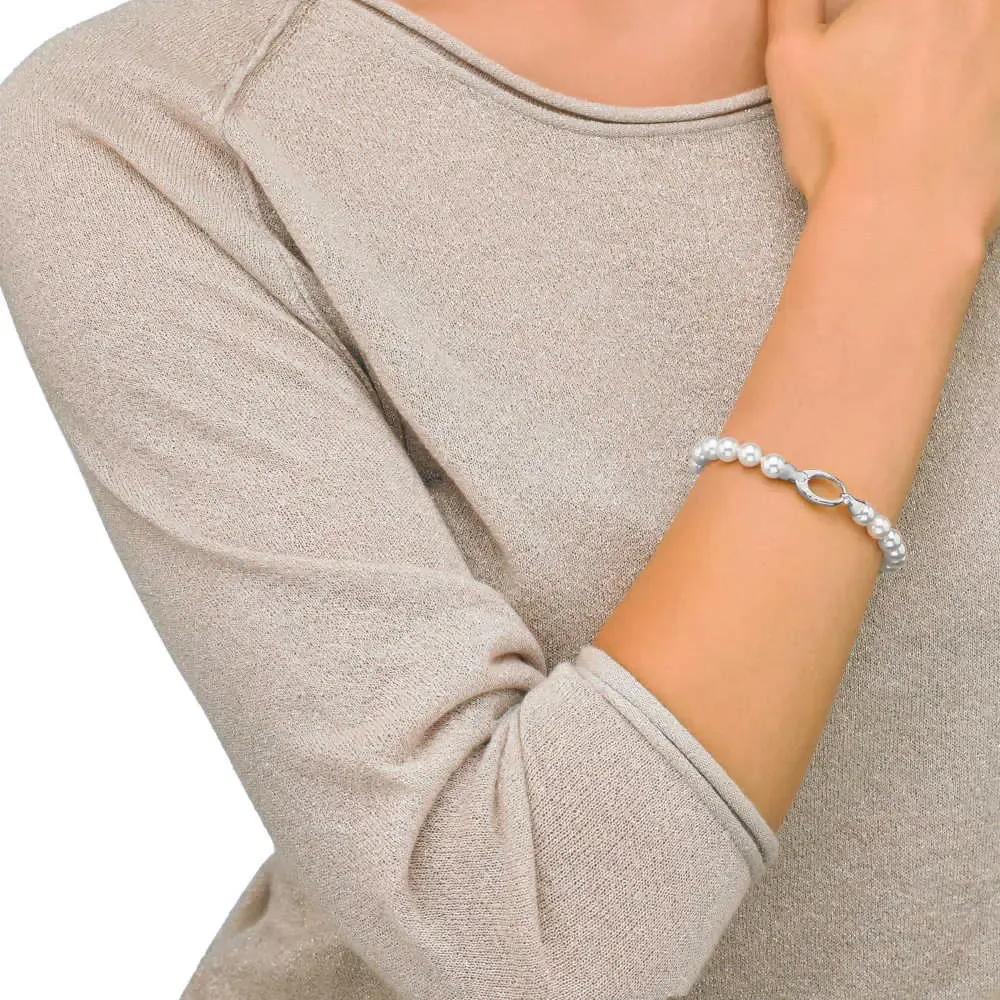 Primer plano de la pulsera de perlas en la muñeca, toma lateral con fondo de prenda beige desenfocado.