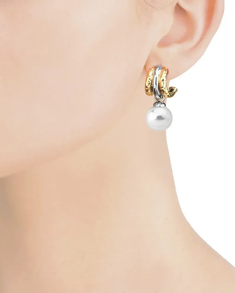 Boucle d'oreille en perle portée au lobe de l'oreille, vue de profil, fond neutre.