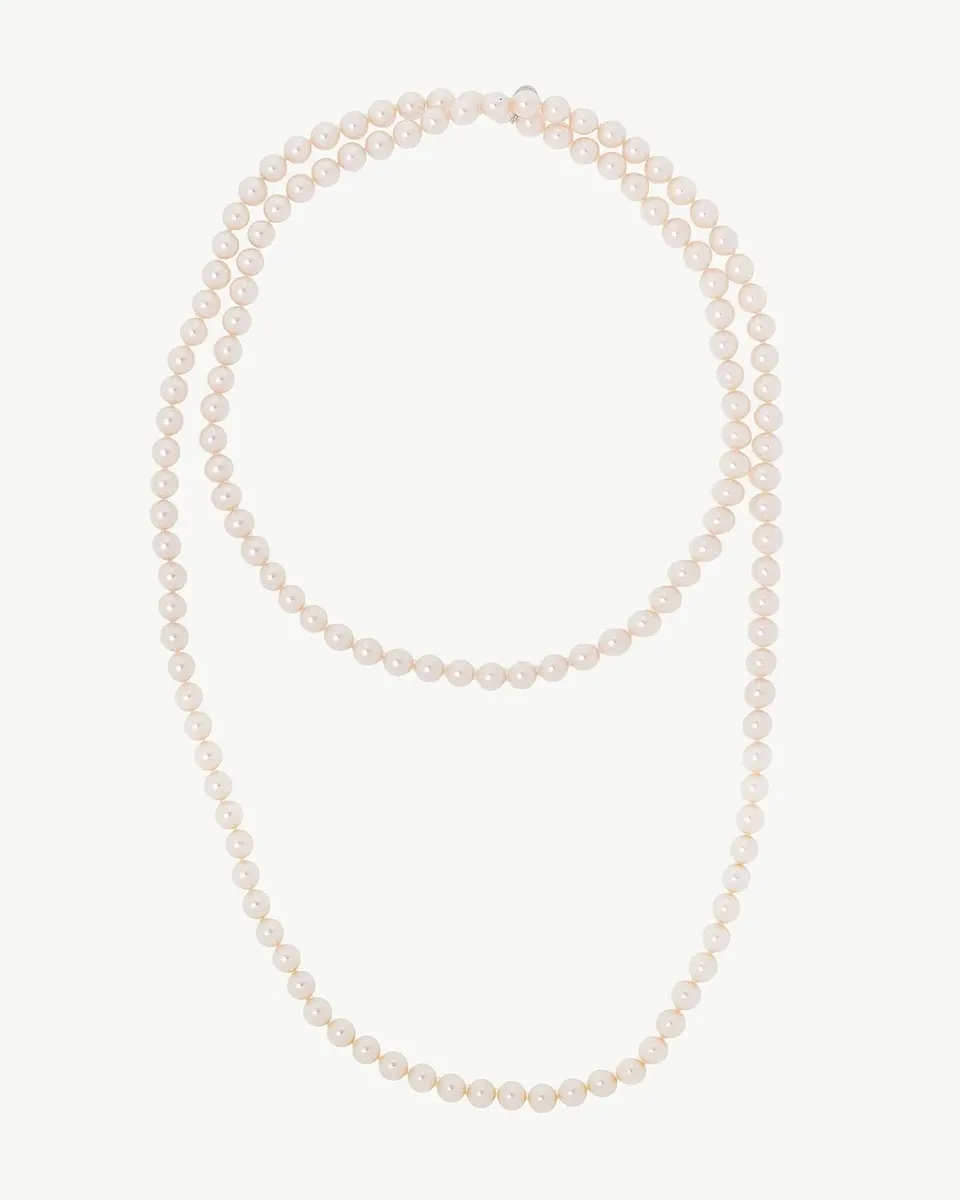 Vista cenital de collar de perlas blancas dispuesto en doble vuelta sobre fondo blanco