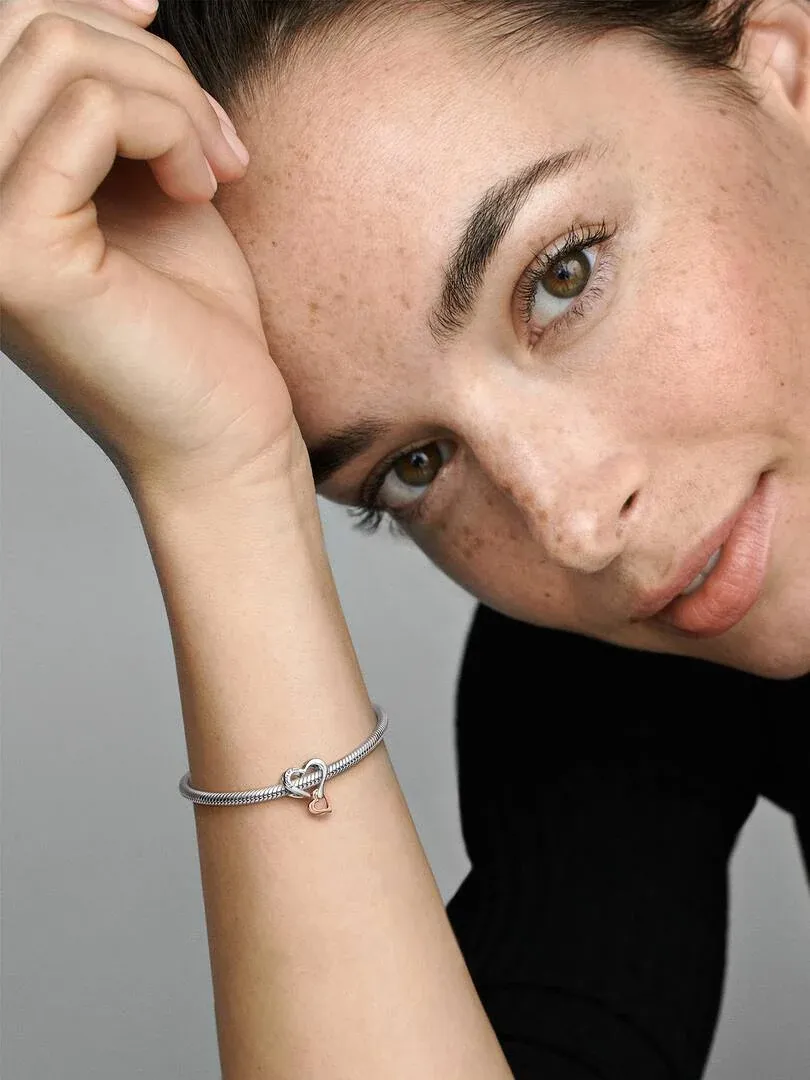 Close-up of the heart charm on a wrist, side view on a model with a neutral background.