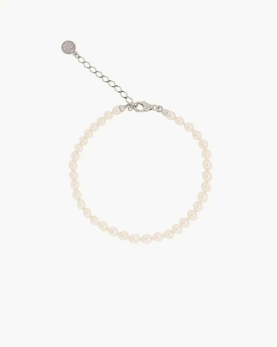 Pulsera de perlas dispuesta en círculo sobre fondo blanco, vista cenital con cierre y cadena de extensión.