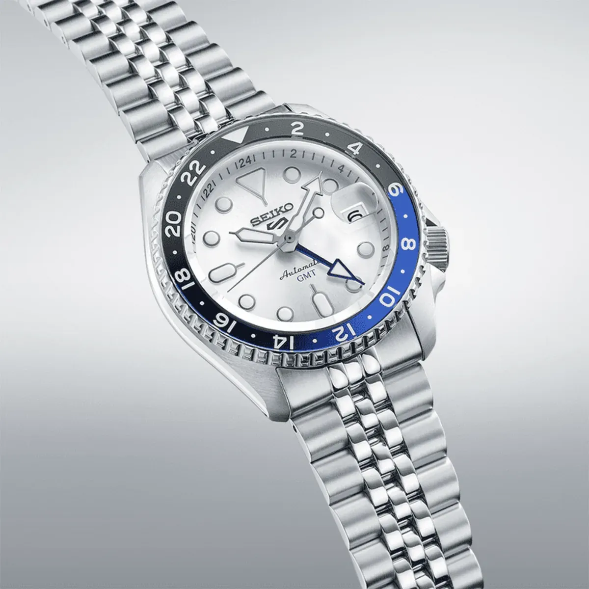 Perspective view of the watch on a neutral gradient background, showing the case, dial, and steel bracelet.