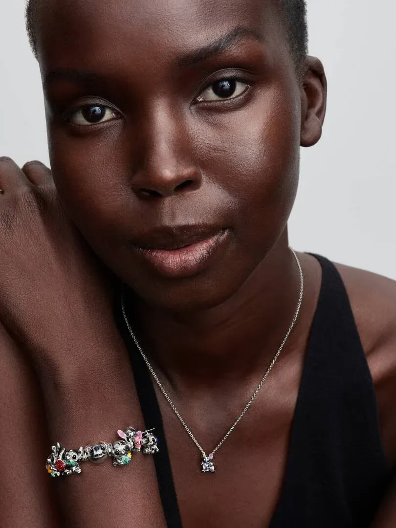 Nahaufnahme eines Models mit dem Stitch-Charm und einer Silberkette, Frontansicht vor neutralem Hintergrund.