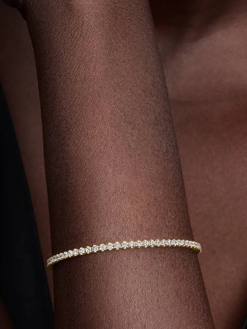Close-up of the tennis bracelet on a wrist, side view with a blurred dark background.