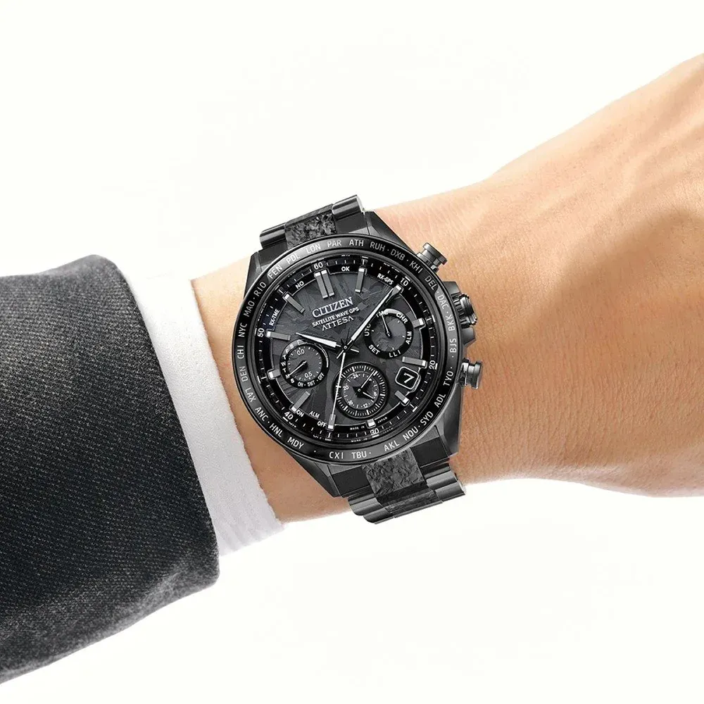 Reloj puesto en muñeca masculina con camisa blanca y traje oscuro, fondo neutro claro.