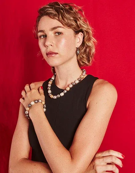 Modelo con collar de perlas barrocas y pendientes a juego, sobre fondo rojo vibrante, plano medio.
