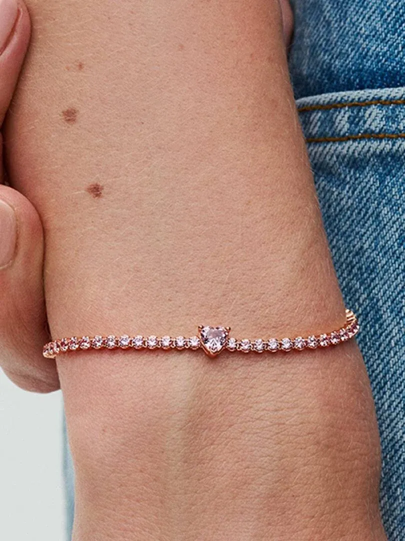 Close-up of the pink crystal bracelet on a wrist, side view against a blue denim background.