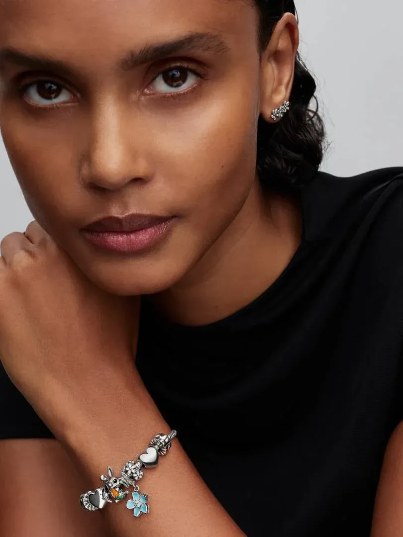 Close-up of bracelet with Stitch charm and silver earrings on a model, neutral background.