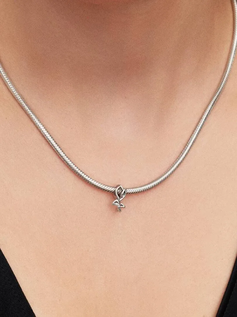 Gros plan du charm tulipe sur un collier en argent porté au cou, vue de face avec fond flou.