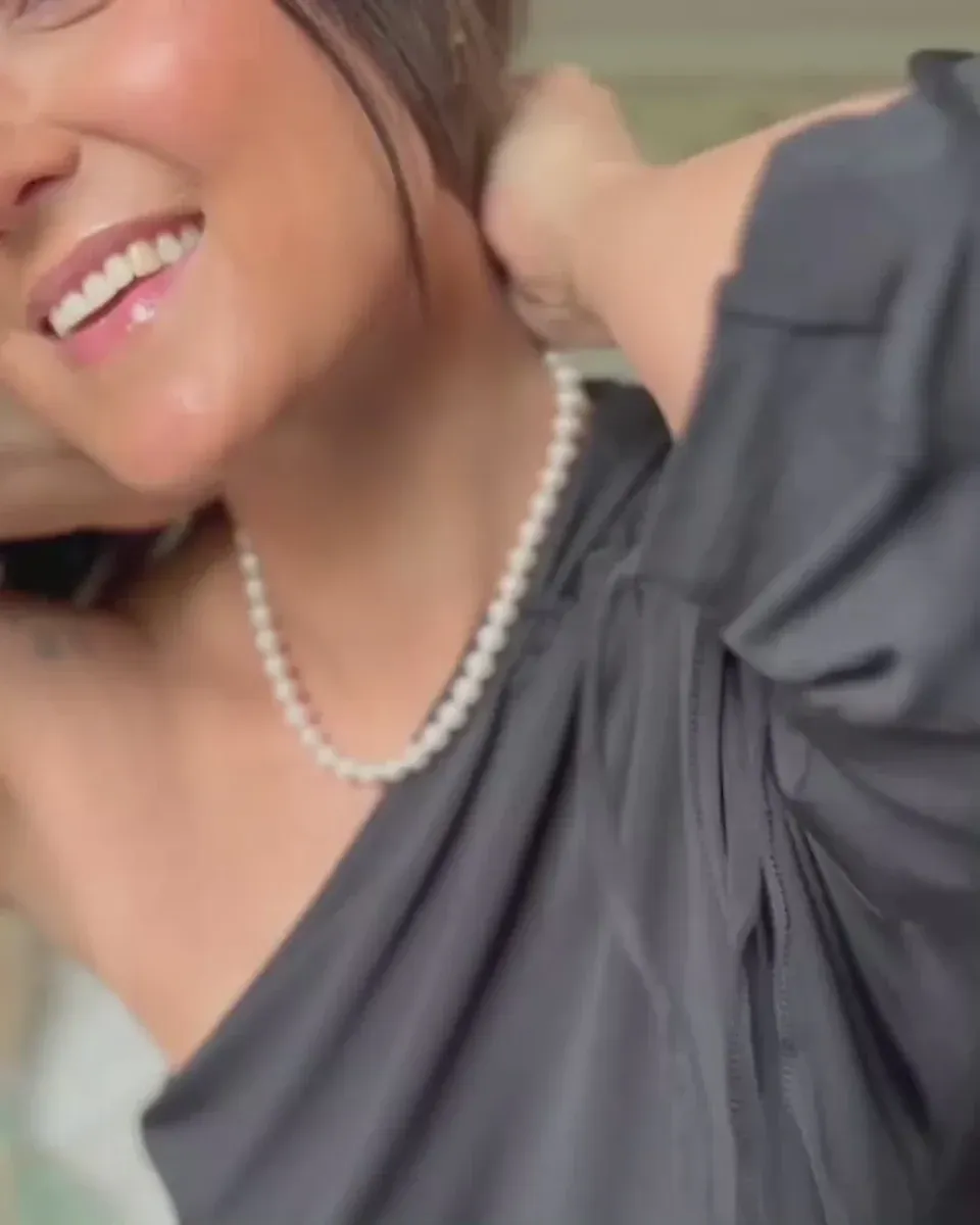 Close-up van de parelketting om de hals van een model, zijaanzicht met wazige achtergrond.