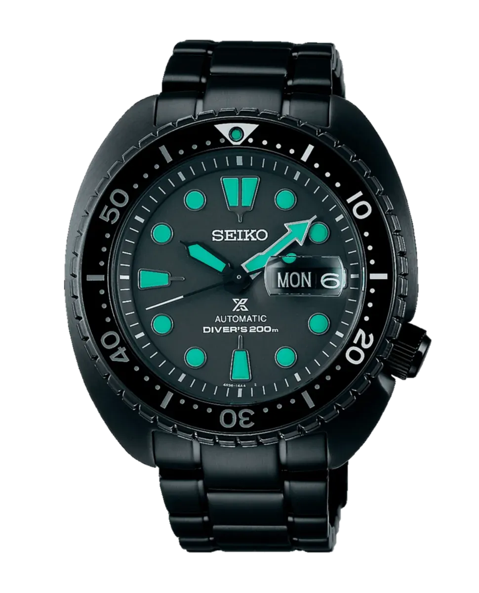 Vista frontal completa de reloj negro con índices luminiscentes verdes sobre fondo blanco.