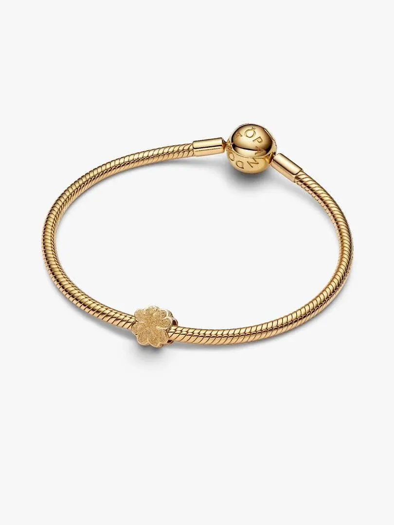 Gold snake chain bracelet with clover charm, angled view on a white background.
