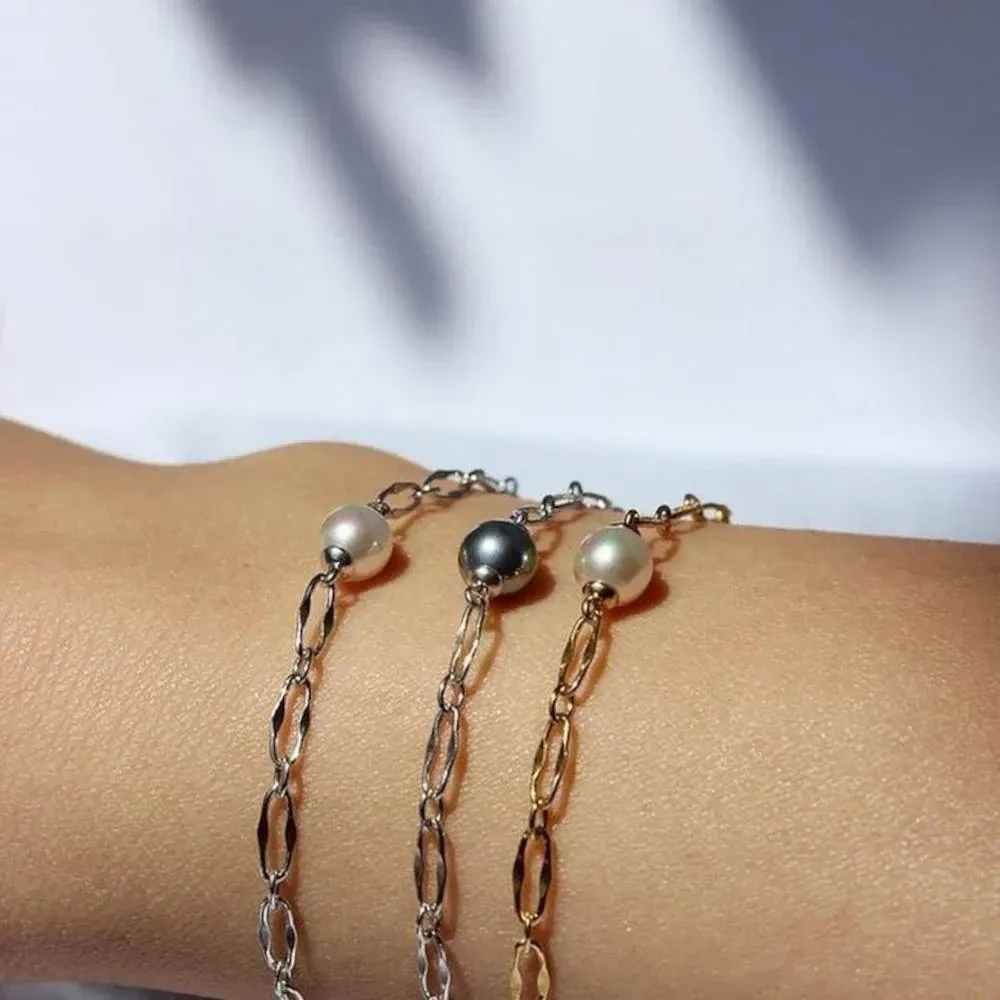 Nahaufnahme von drei Perlenarmbändern an einem Handgelenk, Seitenansicht mit unscharfem Hintergrund.