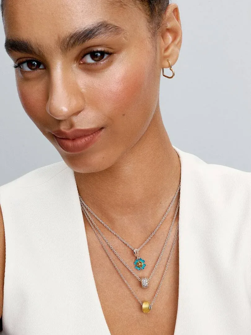 Close-up of three layered necklaces on a model's neck, light neutral background.