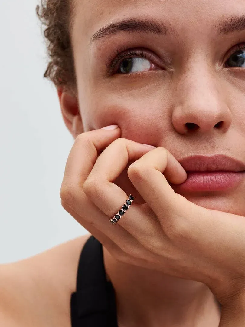 Close-up of the black crystal ring on a model's finger, side view against a neutral background.
