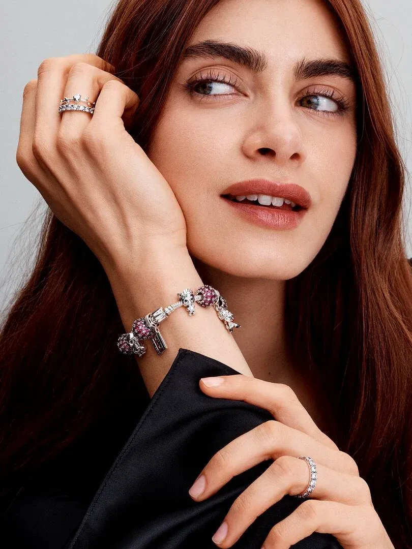 Close-up van model met armband en ringen, zijaanzicht met focus op de sieraden tegen een neutrale achtergrond.