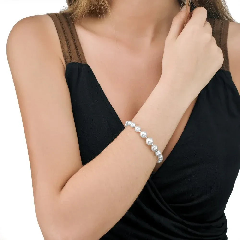 Primer plano de la pulsera de perlas en la muñeca de una modelo, toma lateral sobre prenda negra.