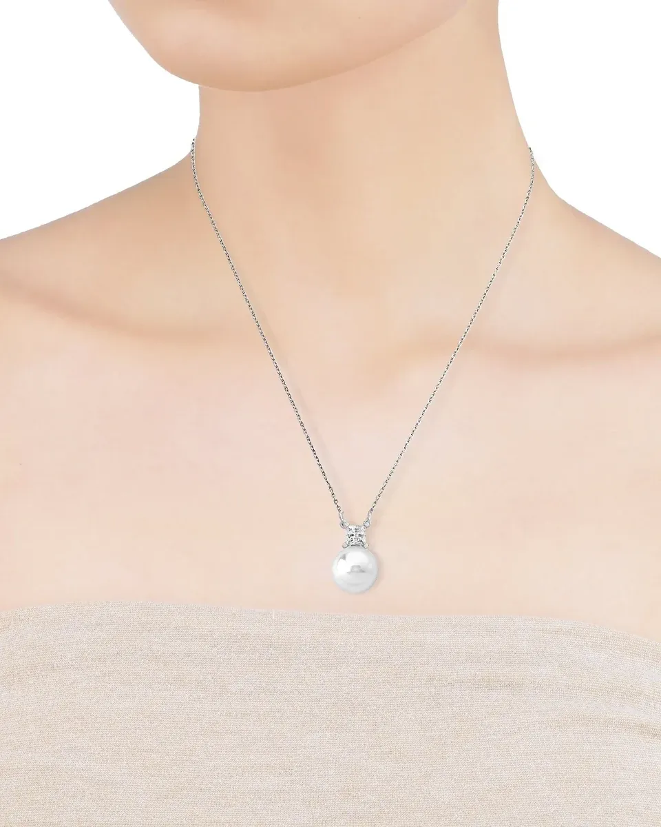 Primer plano del collar con perla blanca sobre el cuello de una modelo, toma frontal centrada.