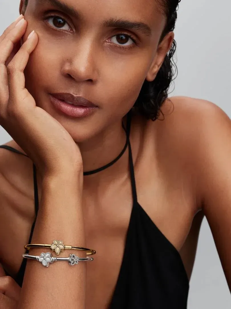 Close-up of floral charm bracelet on wrist, side view against a neutral background.