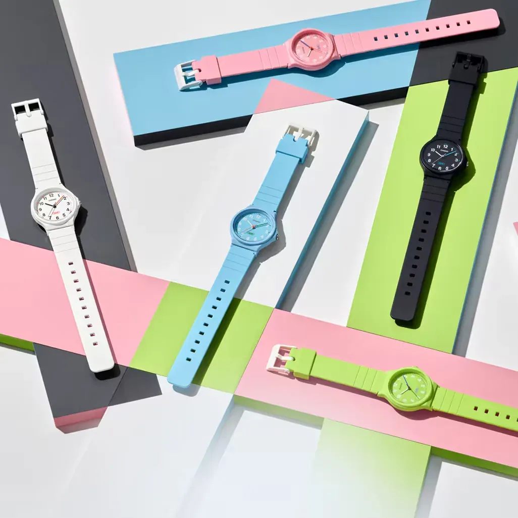 Composición cenital de varios relojes de colores sobre fondos geométricos en tonos pastel y neutros.