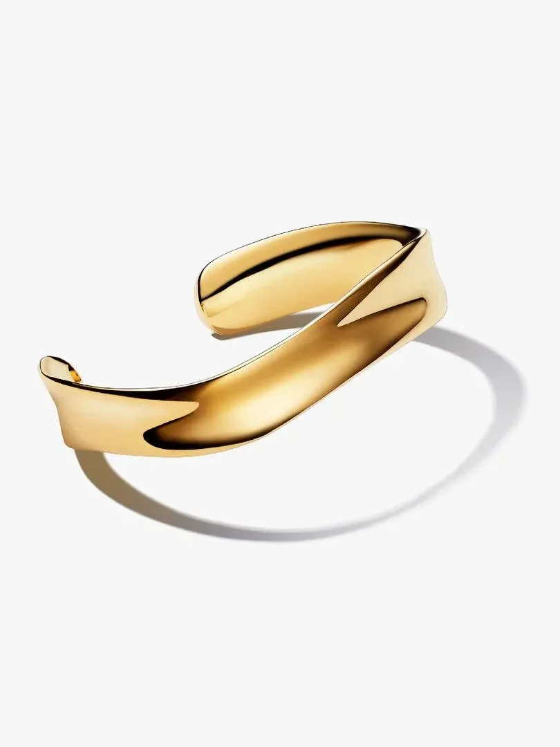Gold bangle with organic wavy profile, side angle view on white background with soft shadow.