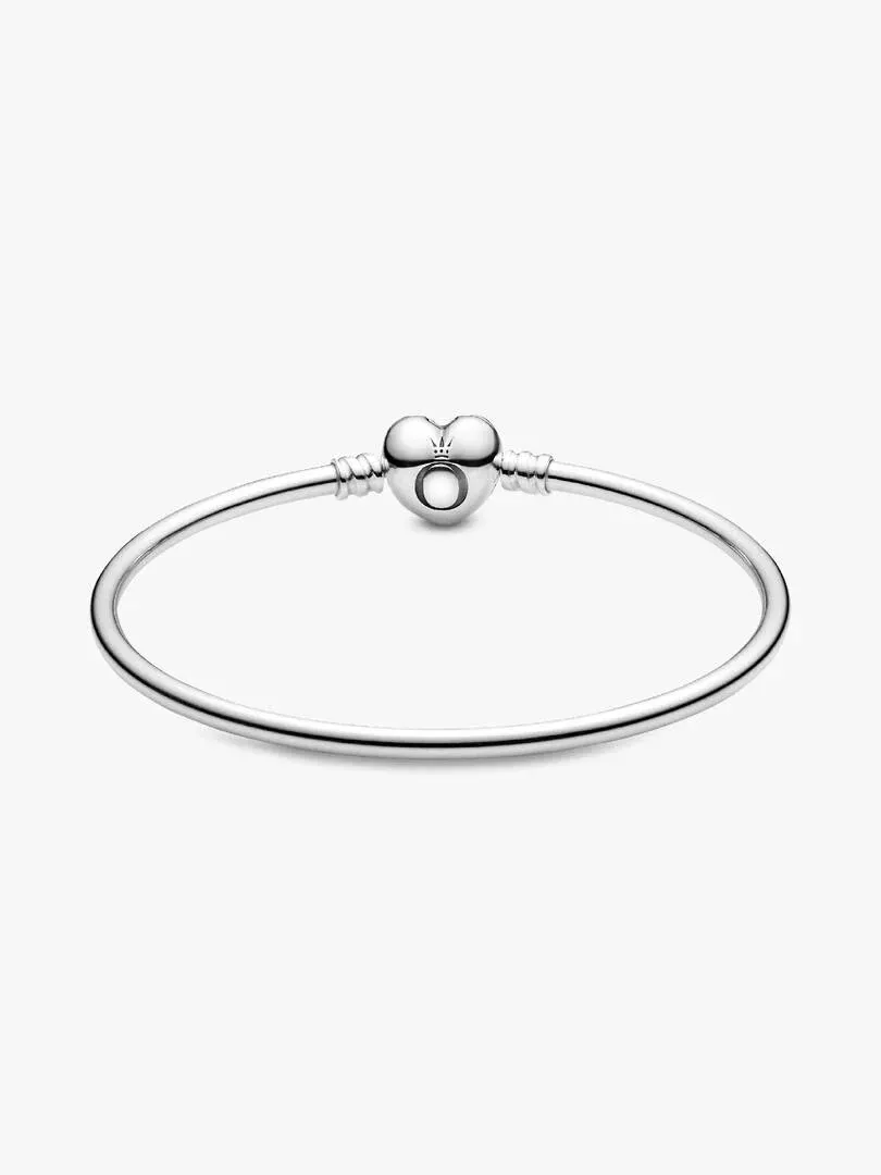 Front view of a silver bangle on a white background, highlighting the heart-shaped clasp.