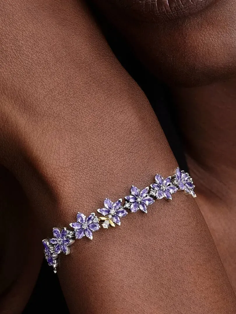 Close-up of the purple flower bracelet worn on a wrist, side view against a dark background.