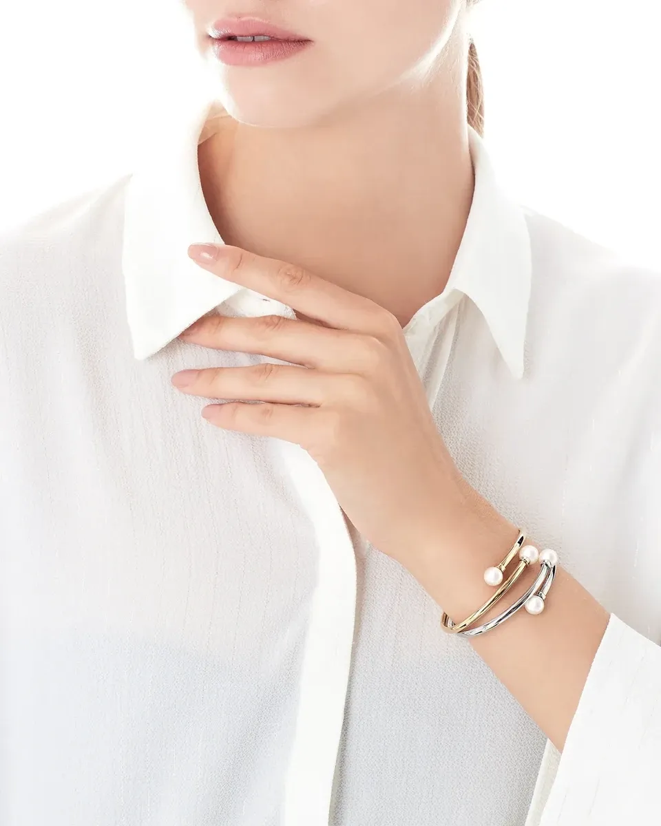 Armband om de pols van een model met wit overhemd, hand op de nek, witte achtergrond.