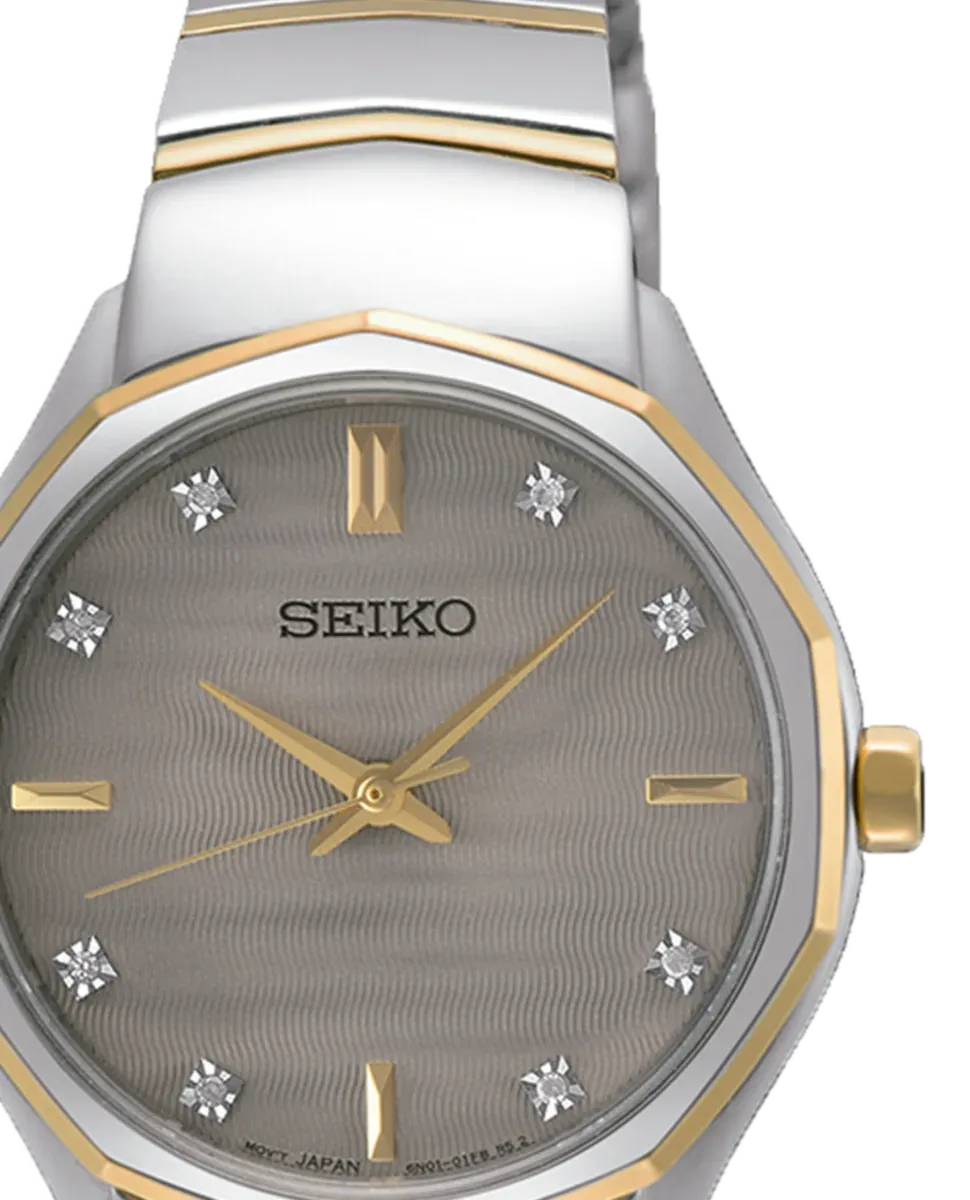 Primer plano de la esfera gris satinada con índices de diamante y bisel dorado, fondo blanco.