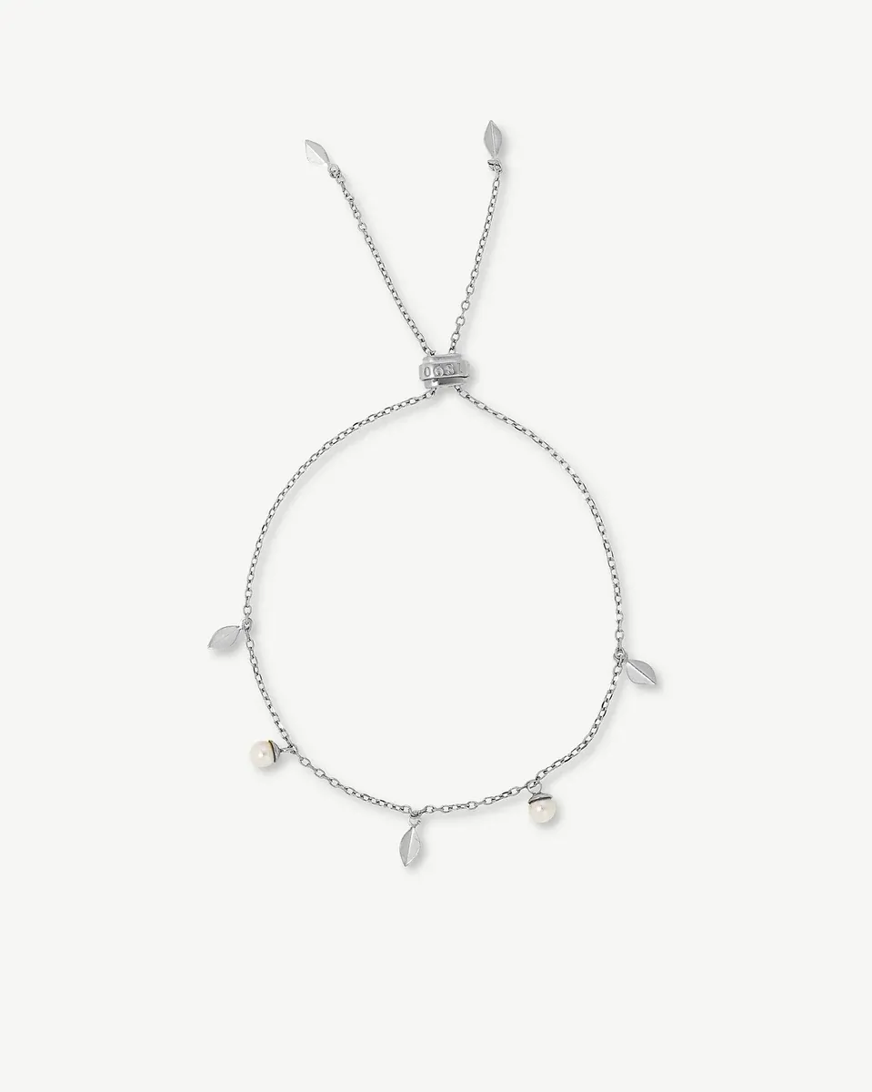 Silver bracelet with leaves and pearls arranged in a circle on a white background, top view.