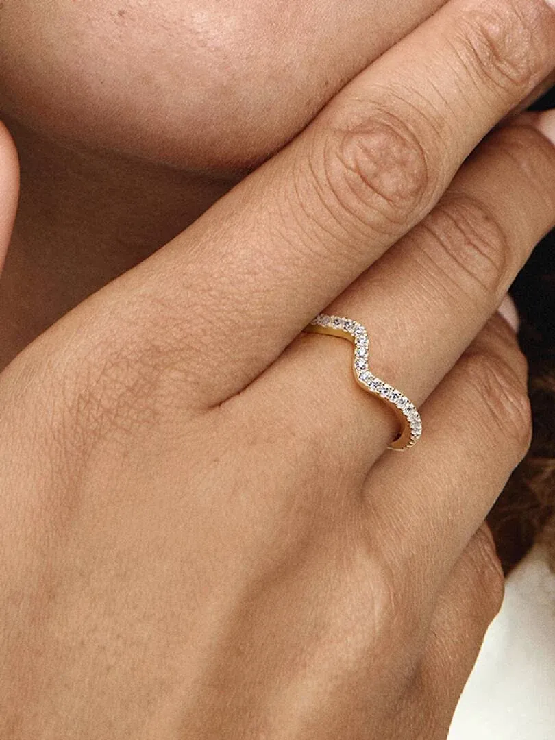 Gros plan latéral de la bague ondulée sertie de zircons portée au doigt.
